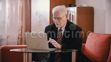 年迈的祖父-戴眼镜的老祖父正在电脑上打字